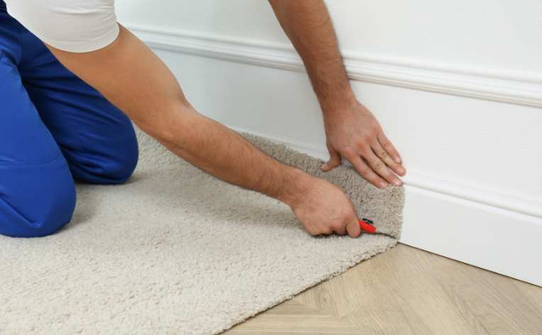 close up of carpet installer cutting new carpet in home